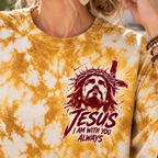 A close-up of a person wearing a yellow and white tie-dye t-shirt with a graphic of Jesus on the chest. The graphic features a crown of thorns, a cross, and the text 'JESUS I AM WITH YOU ALWAYS' in dark red.