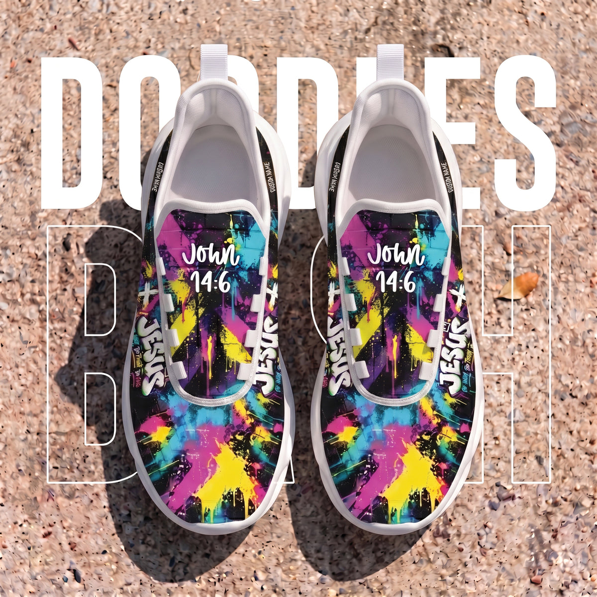 A pair of slip-on sneakers with a vibrant multicolor graffiti-style print featuring pink, yellow, blue, and purple splatters, laid flat on a textured concrete surface. The shoes have white soles and white laces, with the text 'John 14:6' printed on the upper.