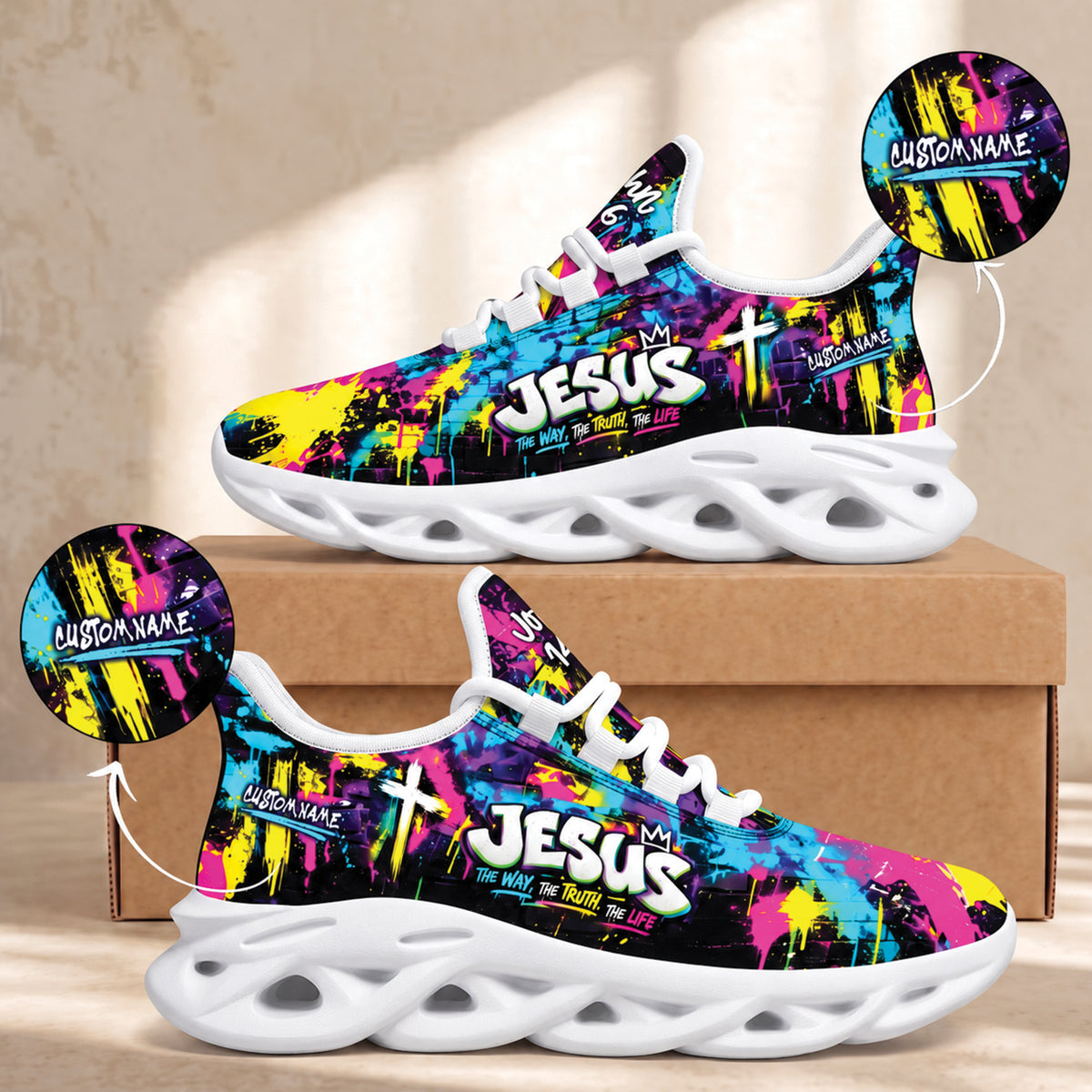 A pair of colorful sneakers displayed on a cardboard box against a beige wall. The shoes have a black base with bright neon paint-splatter graphics in pink, blue, yellow, and purple, plus white 'JESUS' text and cross graphics.